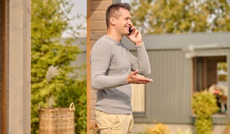 man standing sideways to camera talking on smartphone outdoors